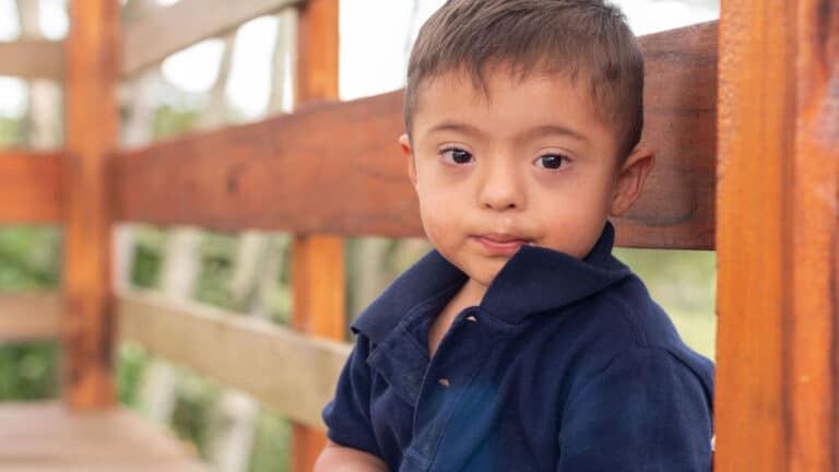 A toddler in a blue shirt looks directly at the camera.