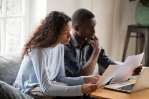 Two parents look at an IEP form, with a computer open nearby.