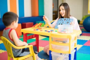 A teacher using blocks and letters to provide special education services to a young boy.