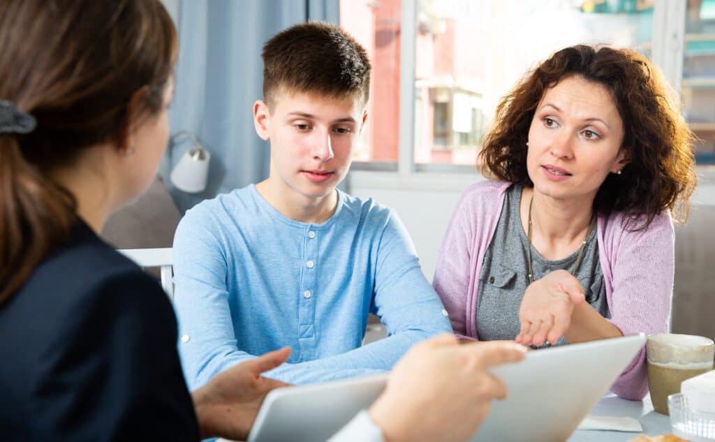 A mom and teenage son look at an IEP draft with a teacher