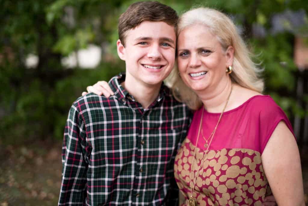 Mother (white woman) and son (white child) standing side by side smiling