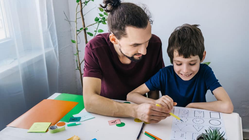 Autistic child during therapy at home with his father learning and having fun.