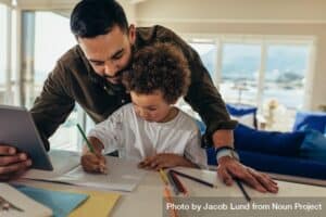 Dad helping his son do schoolwork at a table, demonstrating how to help a child who is struggling in school.