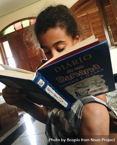 Young girl reading a book to depict literacy development in early childhood