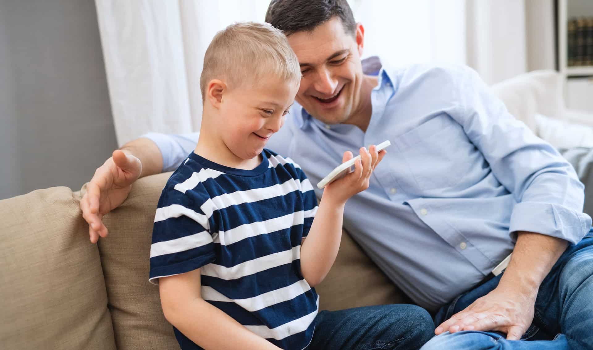 father and son with down syndrome watching a video on their mobile.