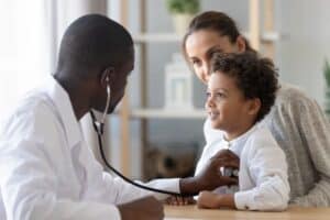 A young boy and his mom with a doctor at the boy’s well-child visit.