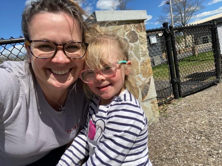 Leah, a white woman, has her arm around her daughter Caroline. They’re both smiling at the camera.