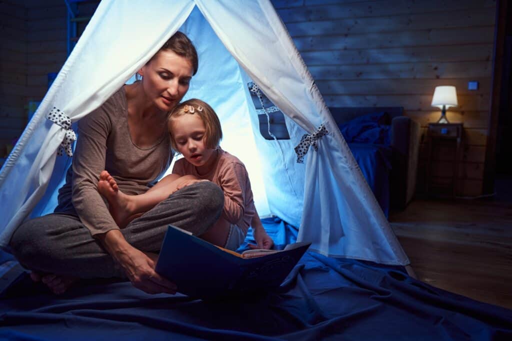 A mom has quiet time with her autistic child at home in a sensory tent