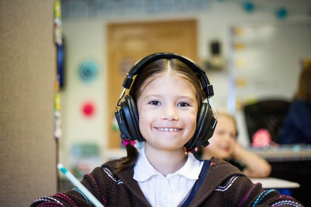 Una niña en un aula de clases, usando audífonos para la cancelación de ruidos