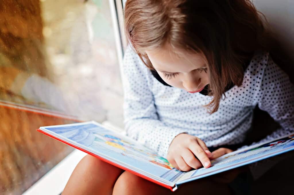 A young girls reads carefully as she learns literacy skills