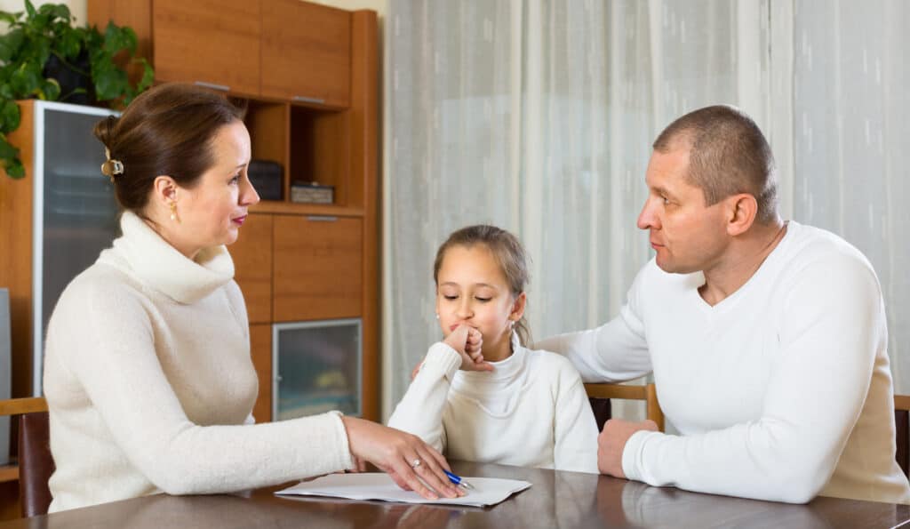 Dos padres discuten un formulario IEP mientras su hija observa