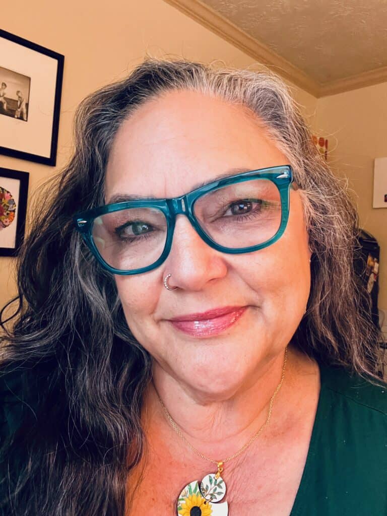 Julia, a white woman with green glasses, smiles slightly at the camera.