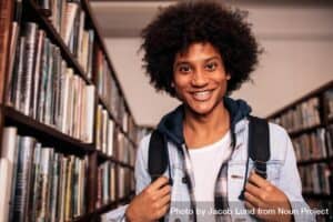 Smiling college student standing in college library