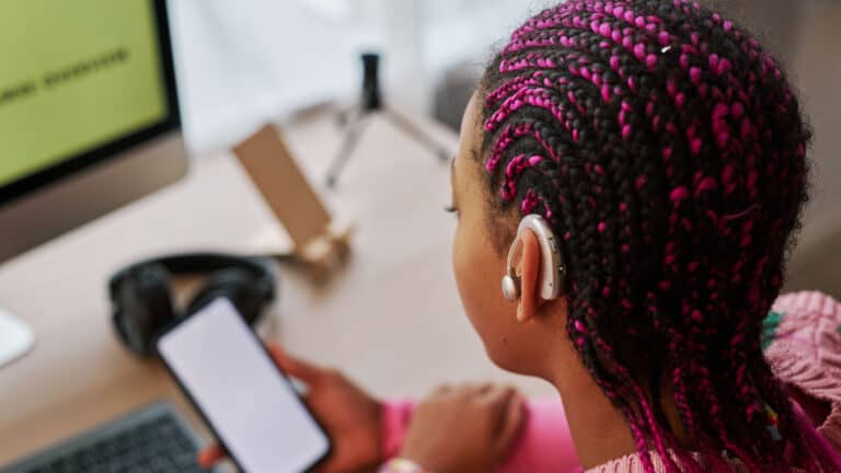 Close-up from back of a Black teen with hearing aids