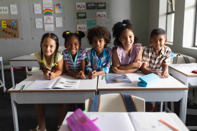 Five elementary students seated, smiling towards the camera.