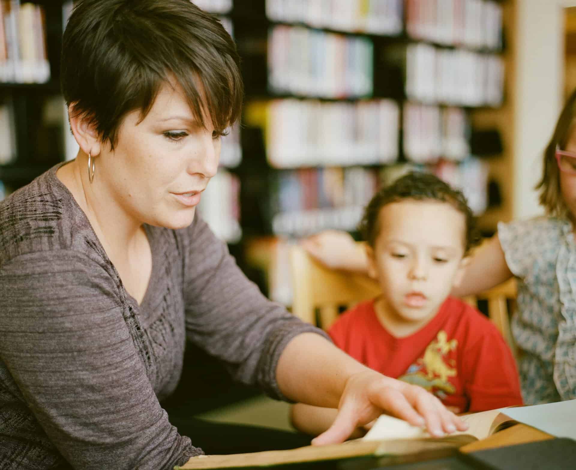 Teacher helps a child in school learn to read.