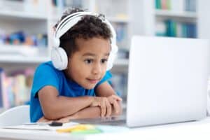 Young boy with headphones working on computer in class